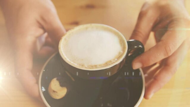 Animation of light spots over hands of caucasian man holding cup of coffee