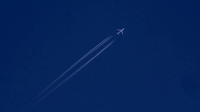 A jumbo jet leaves a vapour trail in a deep blue sky