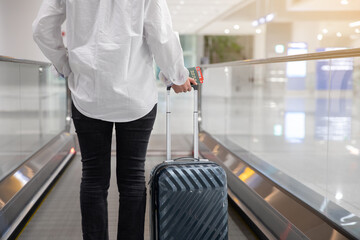 Back view of woman moving using escalator at airport