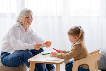 cheerful blonde woman holding felt pen near little daughter.