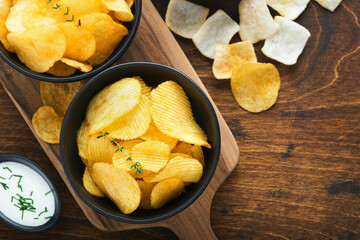 Potato corrugatedchips. Fast food. Crispy potato chips ceramic black bowl with sour cream sauce and...