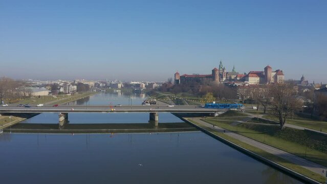 Blue tram rides over Grunwaldzki bridge at Vistula river,  Wawel castleat the background in Cracow ( Krakow), Poland. Static video footage.  relaxed morning mood aerial video