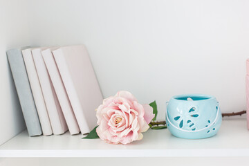 White shelf with books, lush rose and decor in pastel colors.