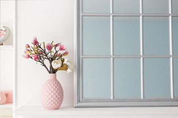 Pink magnolia flowers in a vase on a shelf near a mirror. The concept of minimalism in the interior. - 498287908