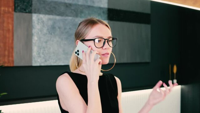 4k Elegant businesswoman in glasses and black dress. Office concept. Brown and modern interior. Talking and working on laptop.