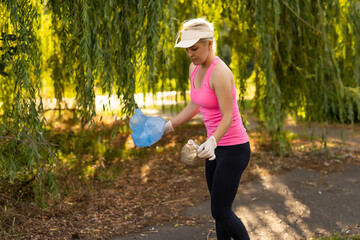 Young beautiful volunteer picking up litter in park