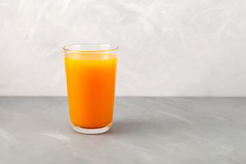 Sea buckthorn juice in tall glass on light grey textured background. Selective focus, copy space