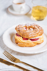 Fototapeta na wymiar Traditional French Dessert called Paris Brest on a light grey background with powder sugar and strawberries