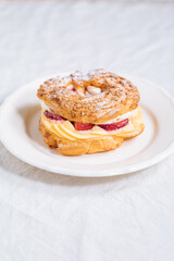 Traditional French Dessert called Paris Brest on a light grey background with powder sugar and strawberries