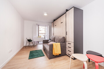 colored side tables, folding sofa bed with cushions, wardrobe with drawers and balcony with folding dining table