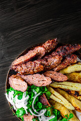 cut Lulia kebab with potato in plate on wooden table background