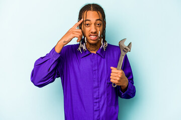 Young mechanic African American man isolated on blue background showing a disappointment gesture...