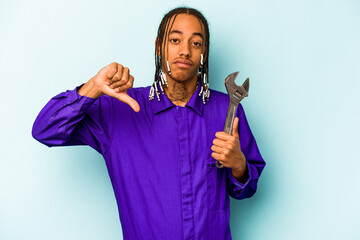 Young mechanic African American man isolated on blue background showing a dislike gesture, thumbs...