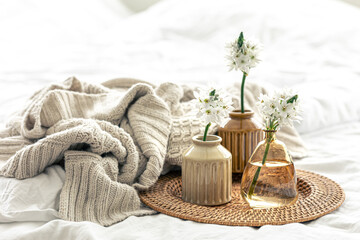 Home composition with flowers in vases and a knitted element.