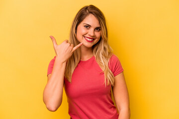 Young caucasian woman isolated on yellow background showing a mobile phone call gesture with fingers.