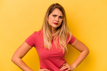 Young caucasian woman isolated on yellow background frowning face in displeasure, keeps arms folded.