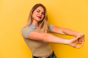 Young caucasian woman isolated on yellow background stretching arms, relaxed position.