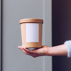 Close up female hands holding paper food container. Delivery concept.