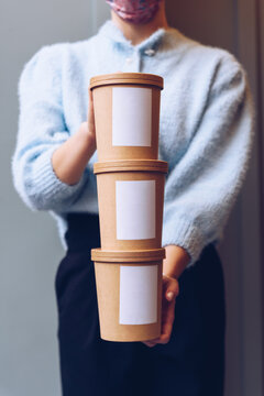 Close up female hands holding paper food containers. Delivery concept.