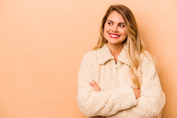 Young caucasian woman isolated on beige background smiling confident with crossed arms.