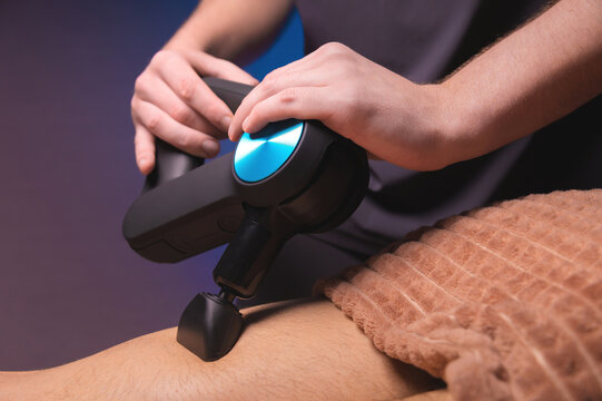 Professional massage with a percussion back massager for a man. Working as a percussion massager