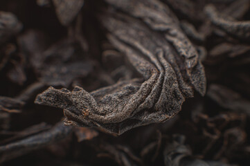 Extreme macro Black loose leaf tea as a background. Texture of dry black tea leaves in shallow depth of field. Dark background. macro mode. black leaf tea closeup
