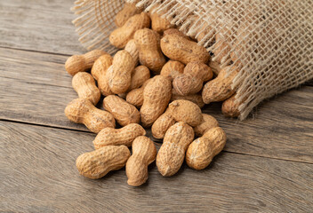 A pile of shelled peanuts in a bag over wooden table