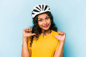 Young hispanic woman wearing a helmet bike isolated on blue background feels proud and self confident, example to follow.