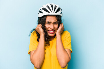 Obraz na płótnie Canvas Young hispanic woman wearing a helmet bike isolated on blue background covering ears with hands.