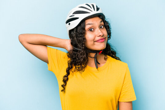 Young Hispanic Woman Wearing A Helmet Bike Isolated On Blue Background Touching Back Of Head, Thinking And Making A Choice.