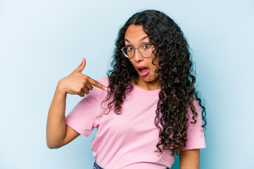 Young hispanic woman isolated on blue background person pointing by hand to a shirt copy space, proud and confident