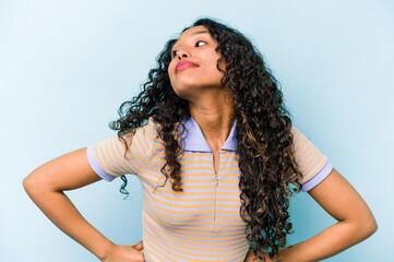 Young hispanic woman isolated on blue background dreaming of achieving goals and purposes