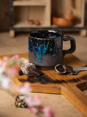 Handmade ceramic coffee mug with coffee beans, hot drink beverage standing on a table. Close up view cozy atmosphere  decorated with blooming sakura.