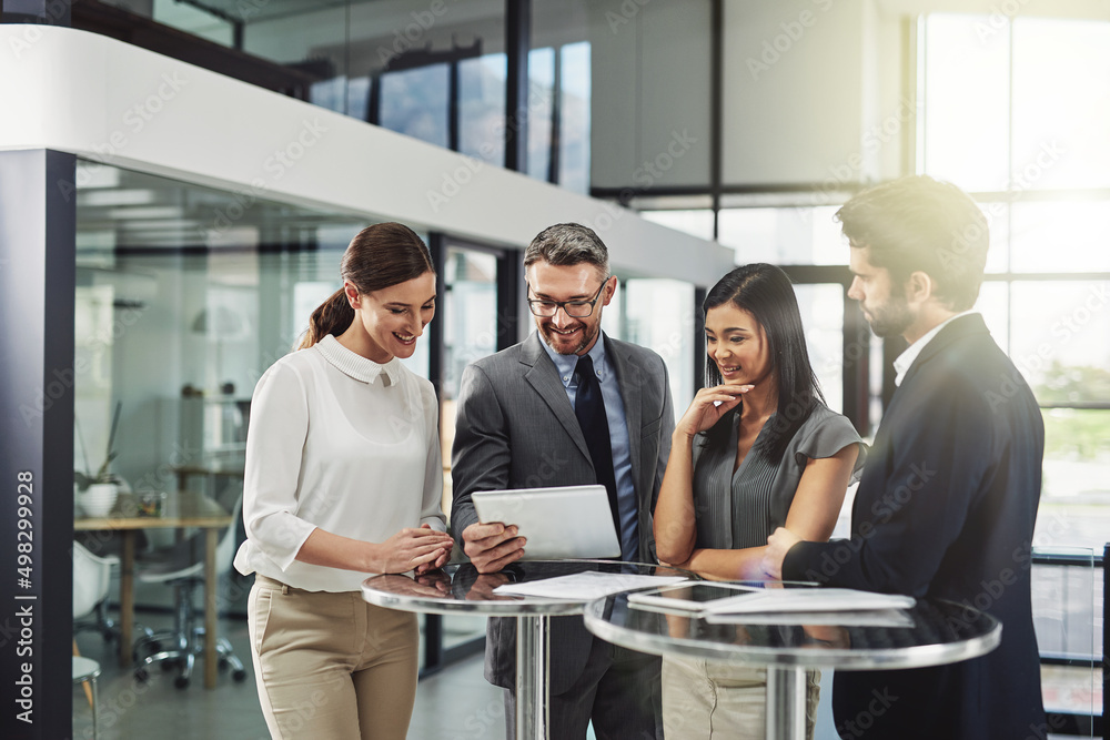 Poster getting positive feedback. shot of a group of colleagues discussing business in the office.