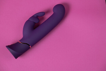 Purple sex toy for woman - vibrator on a pink background