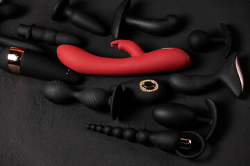Erotic pleasure toys on a black background. Sex gadgets and masturbation devices. Pink dildo...