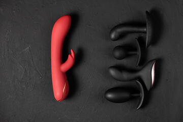Erotic pleasure toys on a black background. Sex gadgets and masturbation devices. Pink dildo...
