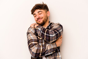 Young hispanic man isolated on white background hugs, smiling carefree and happy.