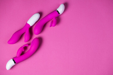 Sex toys. Purple and pink vibrators isolated on a pink background