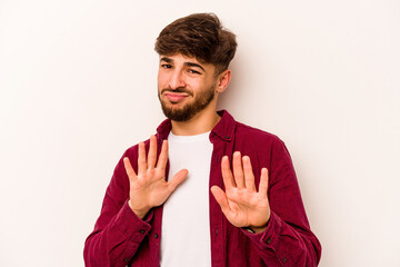 Young hispanic man isolated on white background rejecting someone showing a gesture of disgust.
