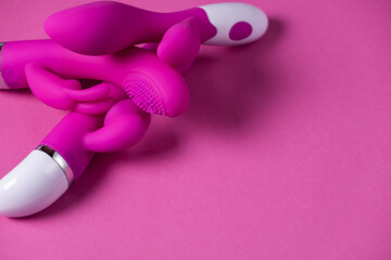 Sex toys. Purple and pink vibrators isolated on a pink background