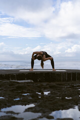 Young woman practice yoga on a beautiful beach at sunrise. Blue sky, ocean, waves, proximity to nature, unity with nature.