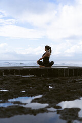 Fototapeta premium Young woman practice yoga on a beautiful beach at sunrise. Blue sky, ocean, waves, proximity to nature, unity with nature.