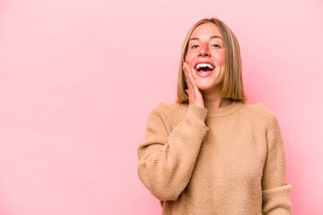 Young caucasian woman isolated on pink background shouts loud, keeps eyes opened and hands tense.