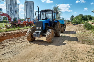 A tractor with a body, a heavy wheeled tractor, an excavator and other construction equipment in the rays of the morning sun.Earthmoving equipment.