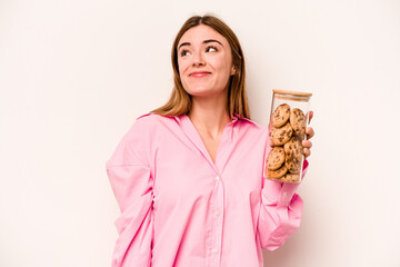 Young caucasian woman holding cookies jar isolated on white background dreaming of achieving goals...