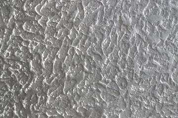 The grainy texture of wall plaster.