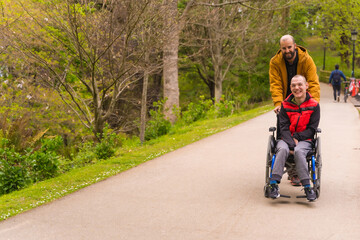 A person with a disability in a wheelchair being pushed by a friend in a public city park, strolling along a path