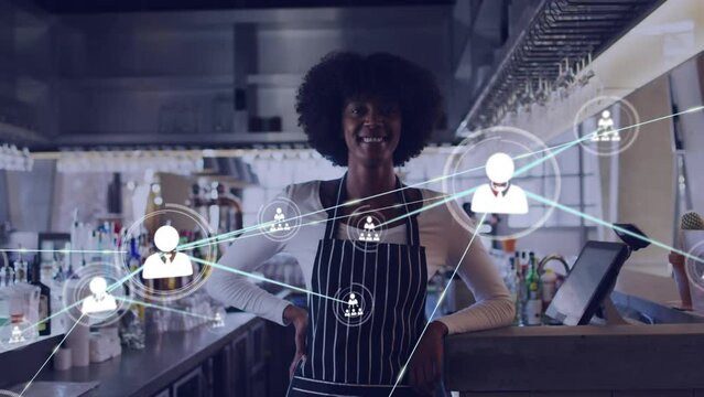 Network of profile icons against portrait of african american bartender smiling at a bar