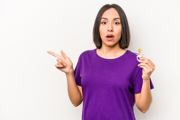 Young hispanic pregnant woman holding pacifier isolated on white background pointing to the side